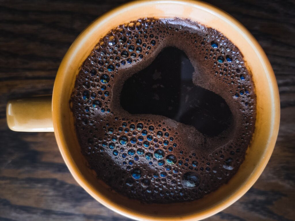 黄色いマグに注がれた黒いコーヒーの俯瞰（イメージ）