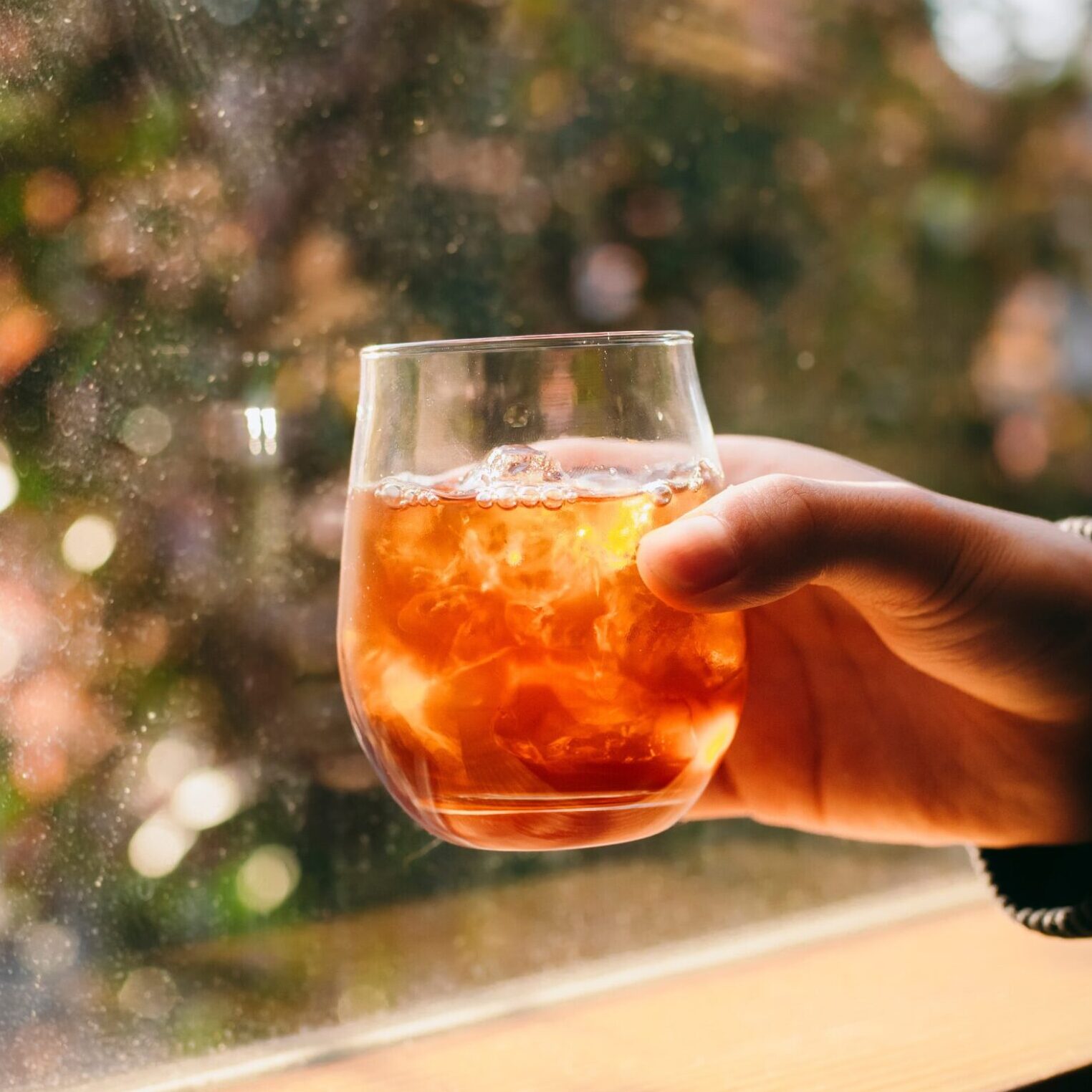 窓辺の飲み物を持つ手